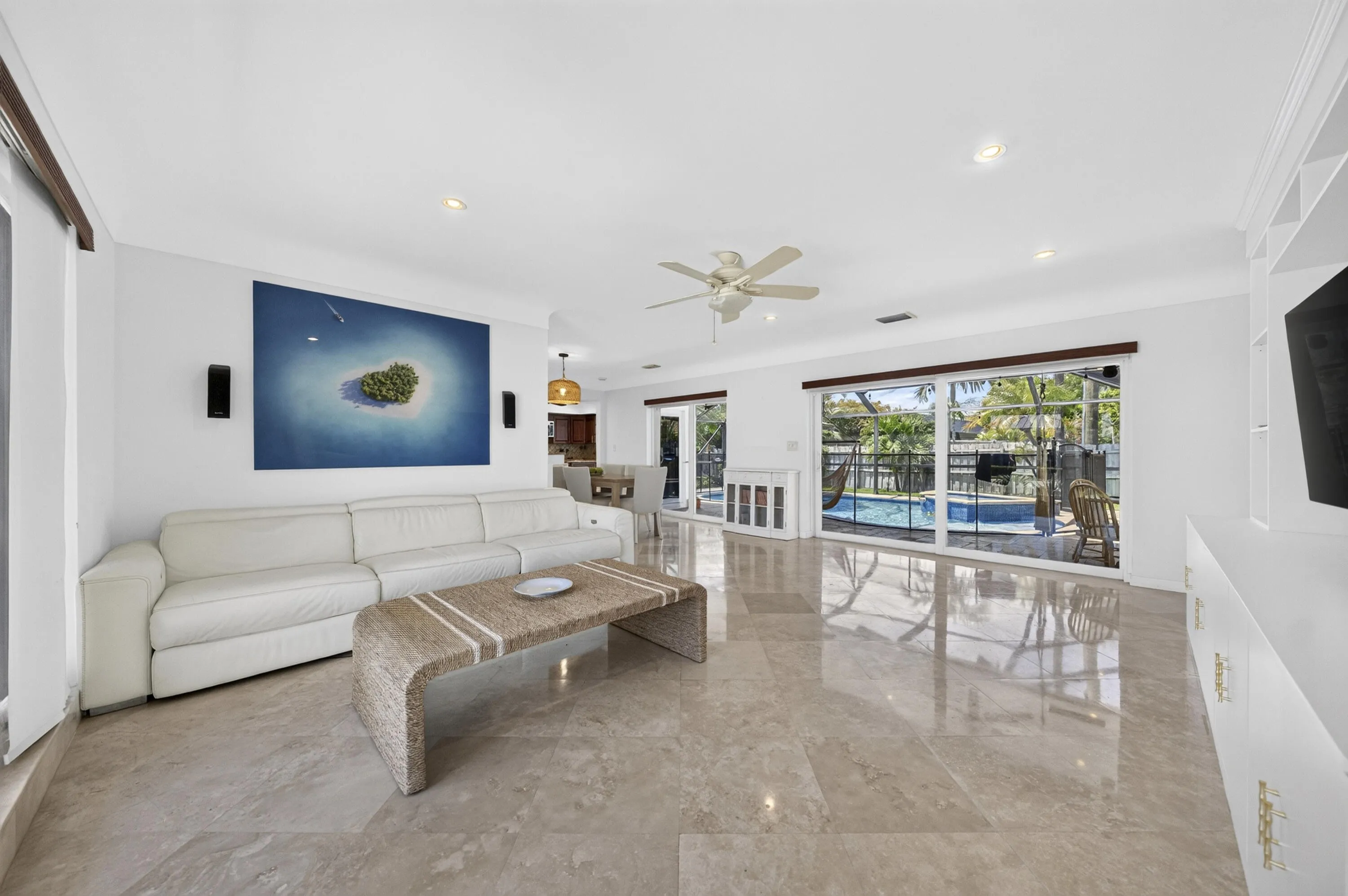 Spacious living area featuring polished Travertine marble flooring, recessed lighting, and a ceiling fan
