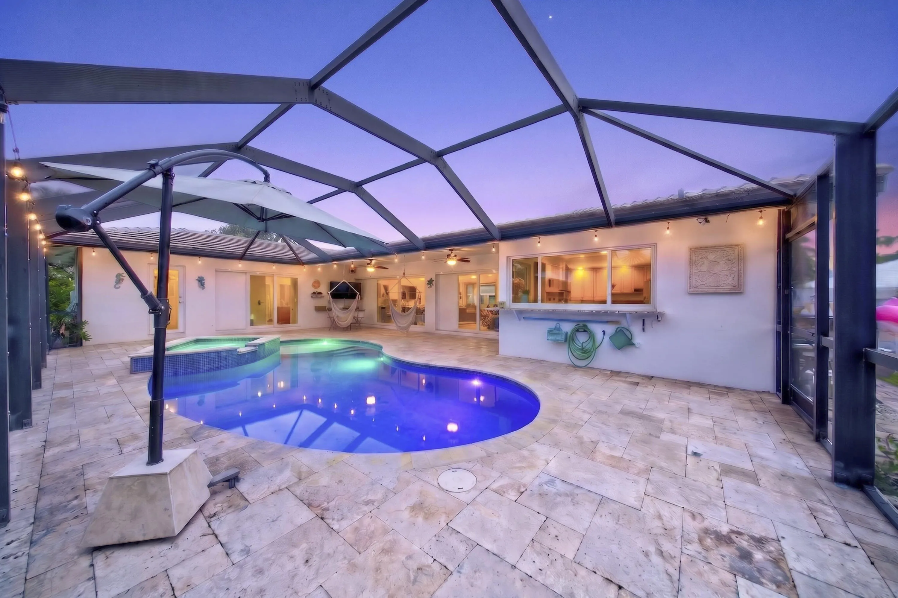 Screened patio featuring a freeform pool, integrated spa, and expansive stone tile decking