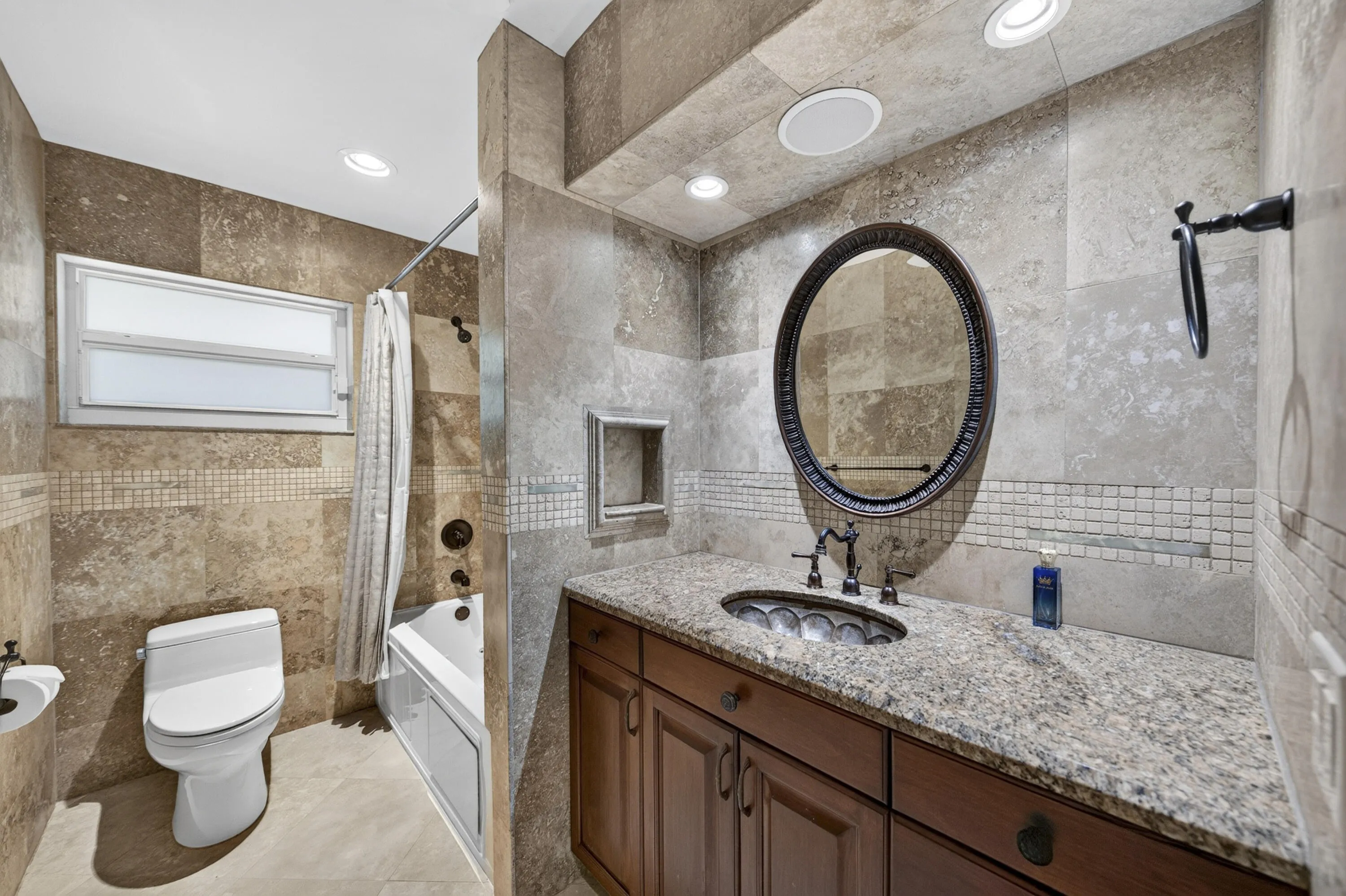2nd full bathroom featuring a granite countertop vanity with a decorative vessel sink, an oval framed mirror, recessed lighting, and tiled walls with decorative mosaic accents
