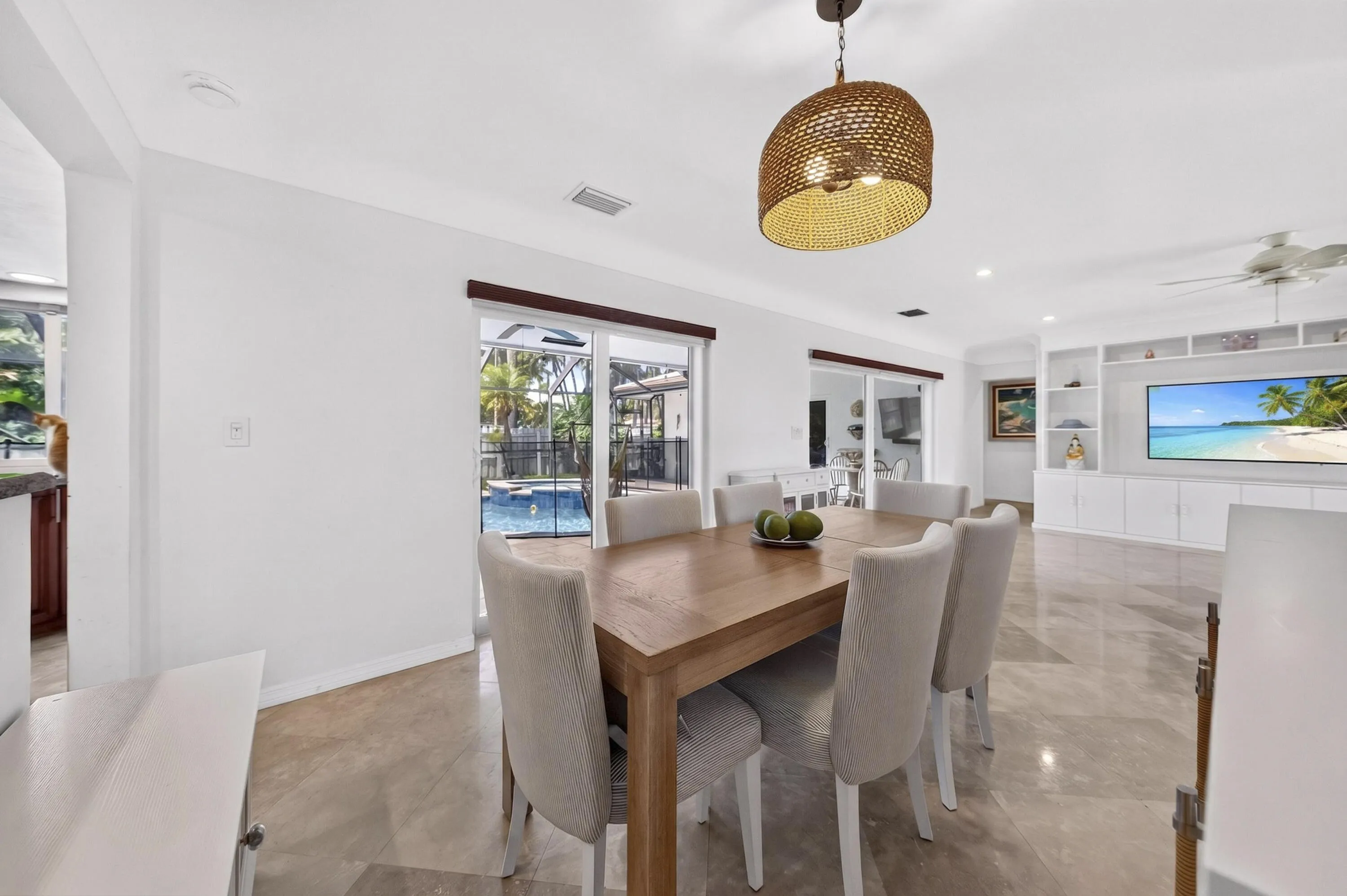Dining area featuring large format tile flooring, a woven pendant light fixture, and direct access to an outdoor pool area through sliding glass doors