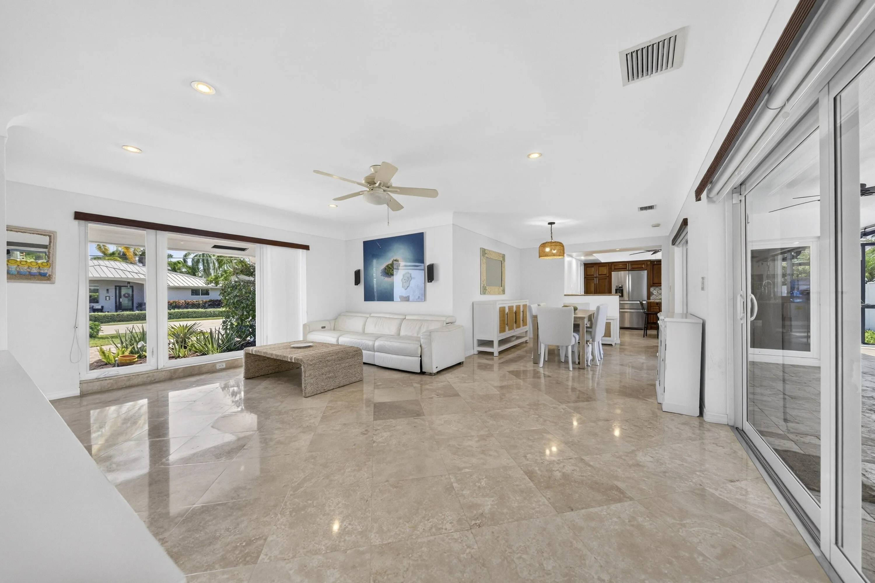 Spacious living area featuring large format tile flooring, recessed lighting, and a ceiling fan