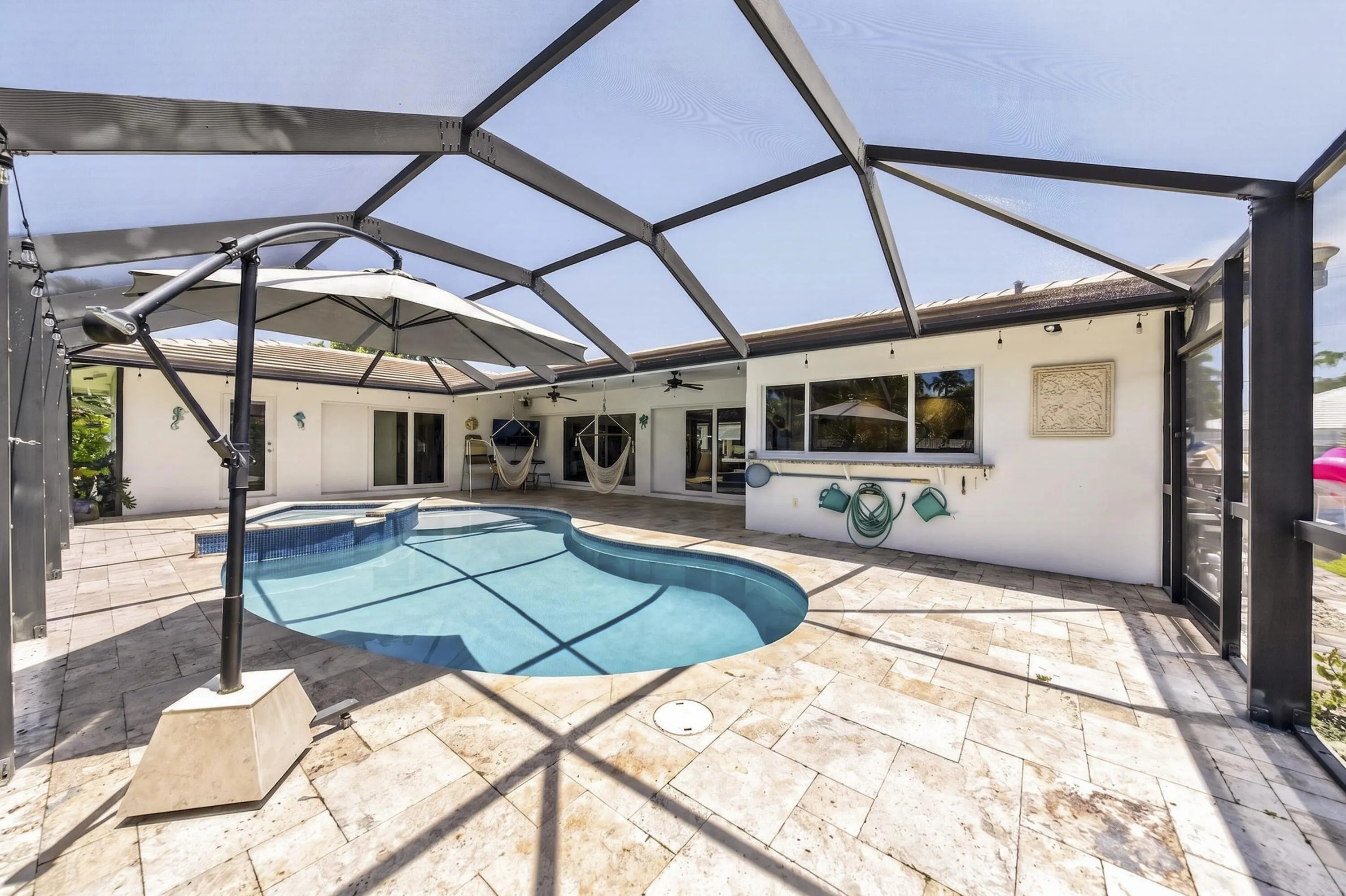 Screened pool enclosure featuring a freeform swimming pool and integrated spa