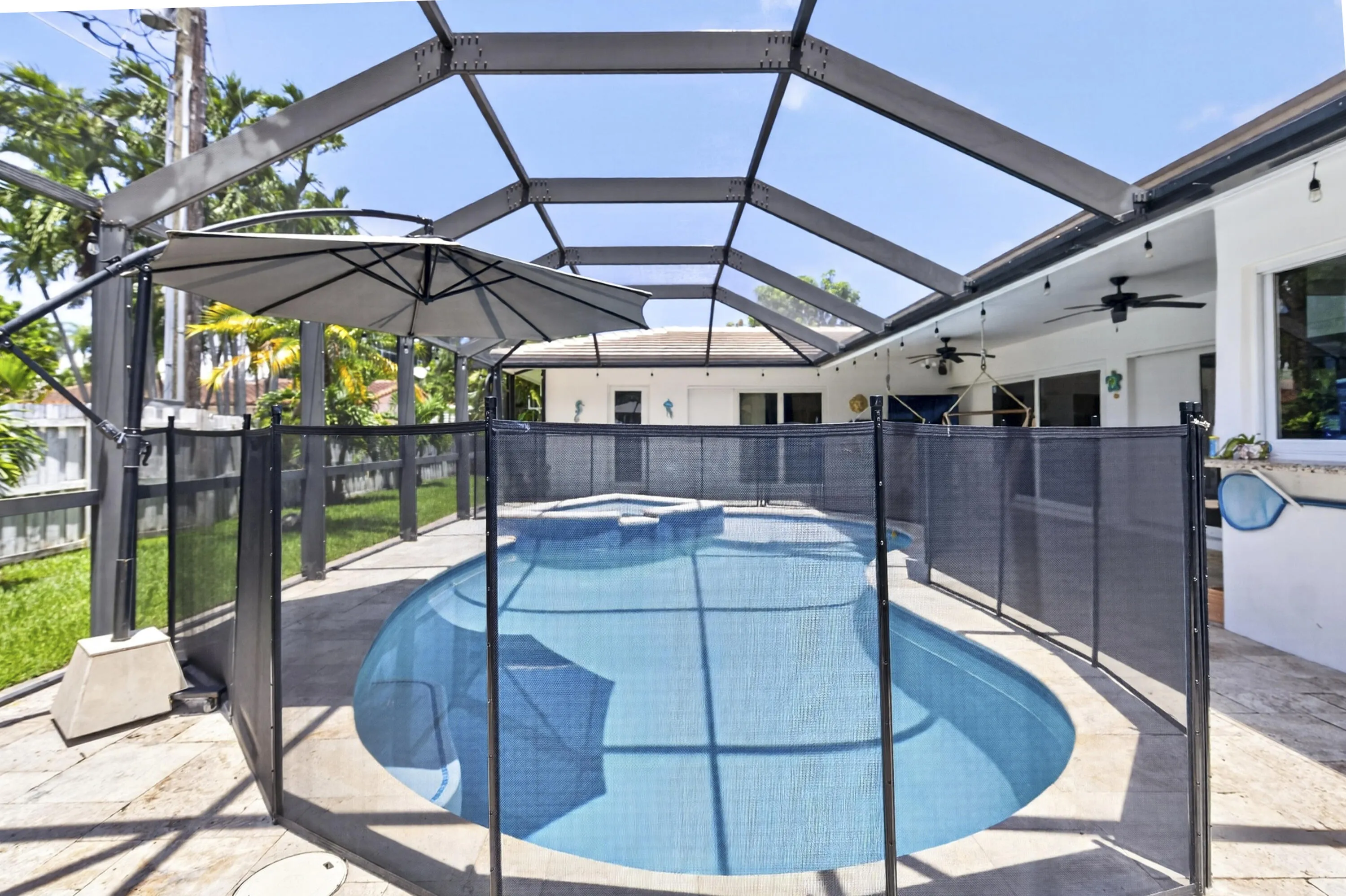 Screened-in outdoor pool enclosure featuring a pool safety fence