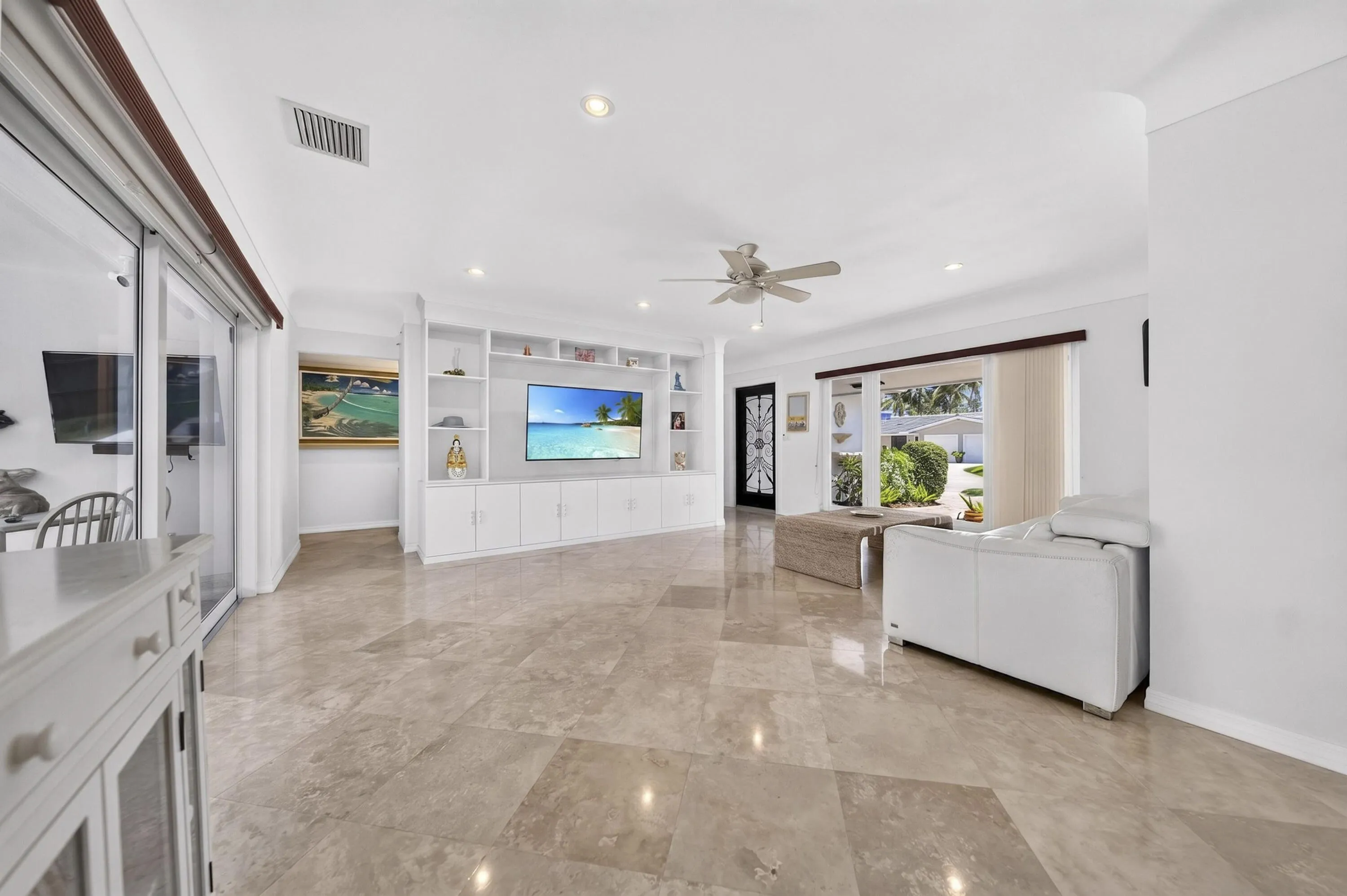 Spacious living area featuring large format Travertine marble flooring, a built-in media center with shelving and lower cabinetry, recessed lighting, and a ceiling fan