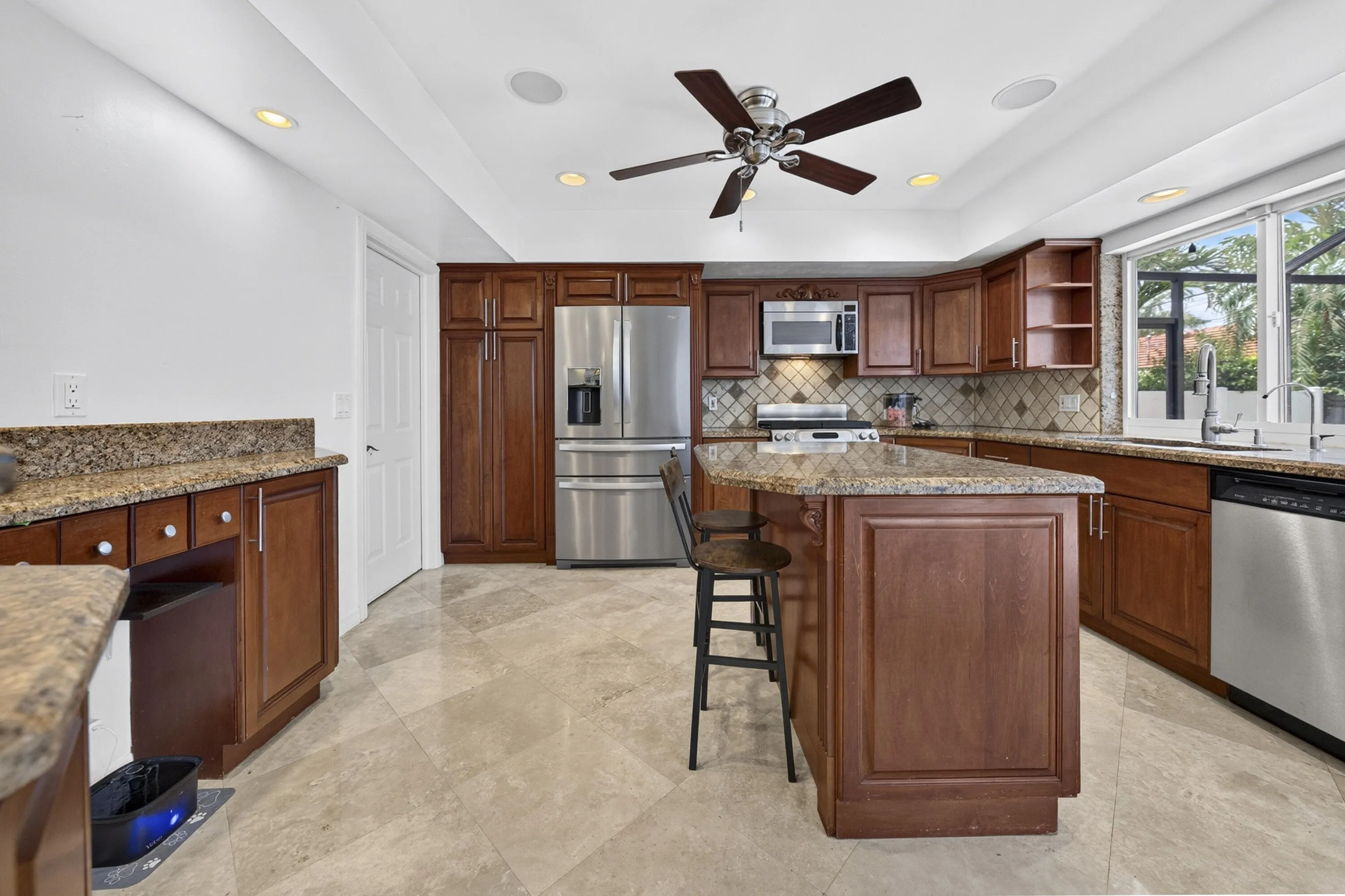 Kitchen featuring wood cabinetry, stainless steel appliances, granite countertops, and tiled flooring