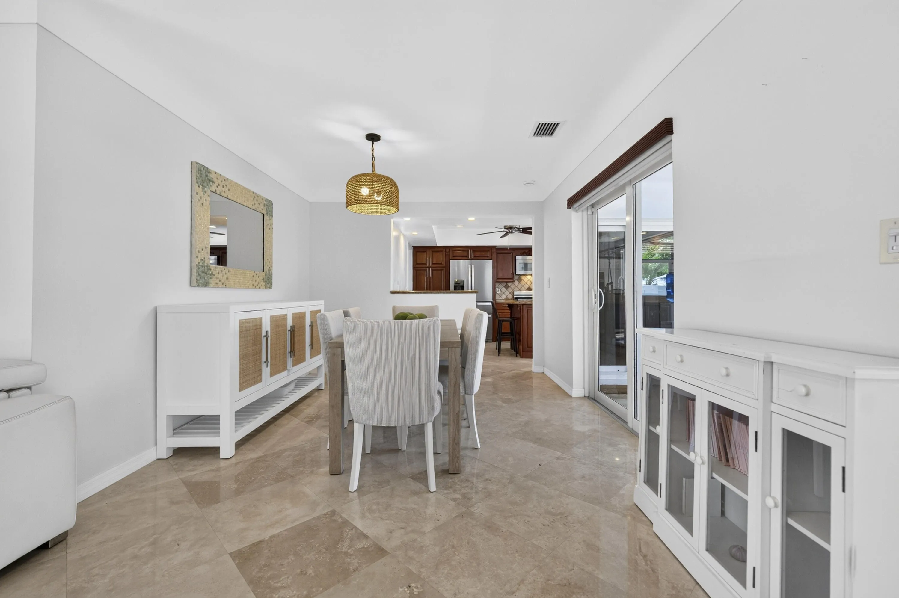 Dining area featuring tile flooring, a woven pendant light fixture, white walls, and sliding glass doors providing access to the exterior
