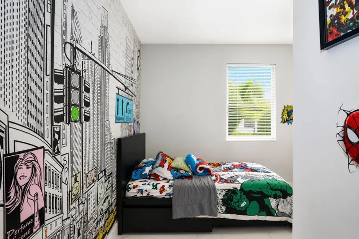 Well-lit interior room featuring a large window with horizontal blinds, a city-themed accent wall, and light-toned flooring