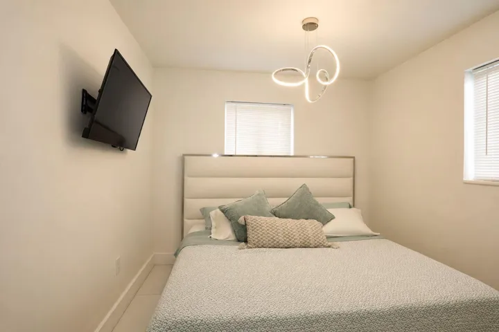 Room featuring light-toned walls, a decorative ceiling fixture, and two windows with blinds