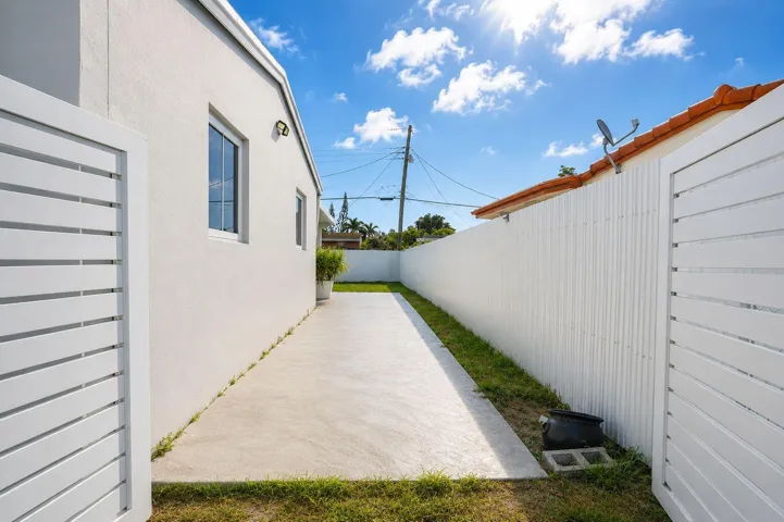Private side yard featuring a concrete patio, white stucco exterior, and a tall white privacy fence