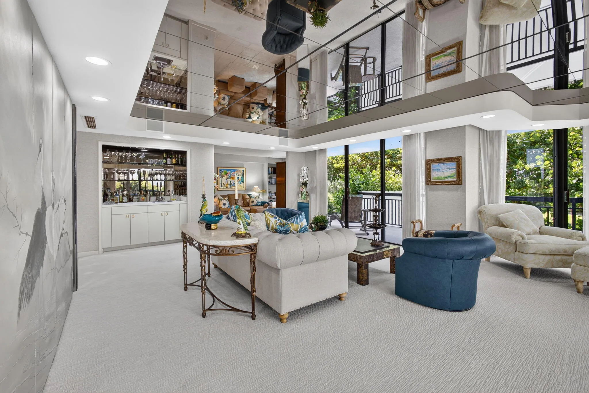 Spacious living area featuring a mirrored ceiling, built-in wet bar with cabinetry, full-height windows, and a second-story balcony overlooking the space