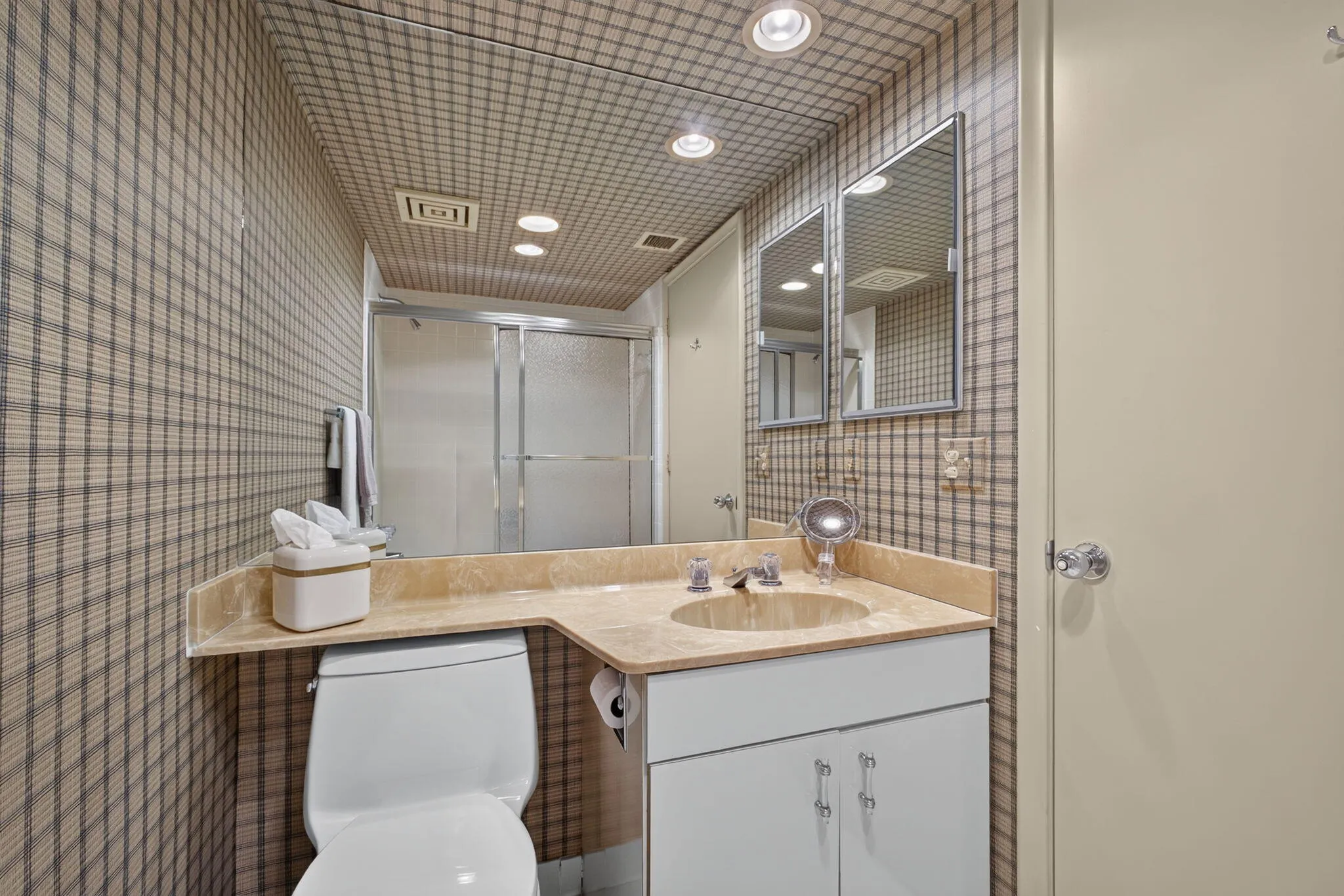 Bathroom featuring patterned wallpaper, a built-in vanity with an integrated sink and stone countertop, recessed lighting, and a shower with frosted glass enclosure