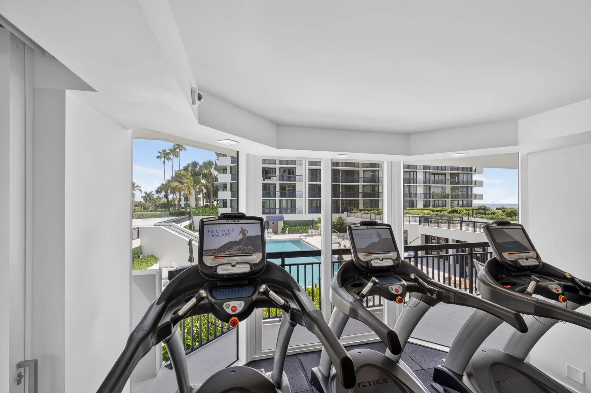 Fitness area featuring floor-to-ceiling windows, panoramic outdoor scenery, a swimming pool, and tropical foliage