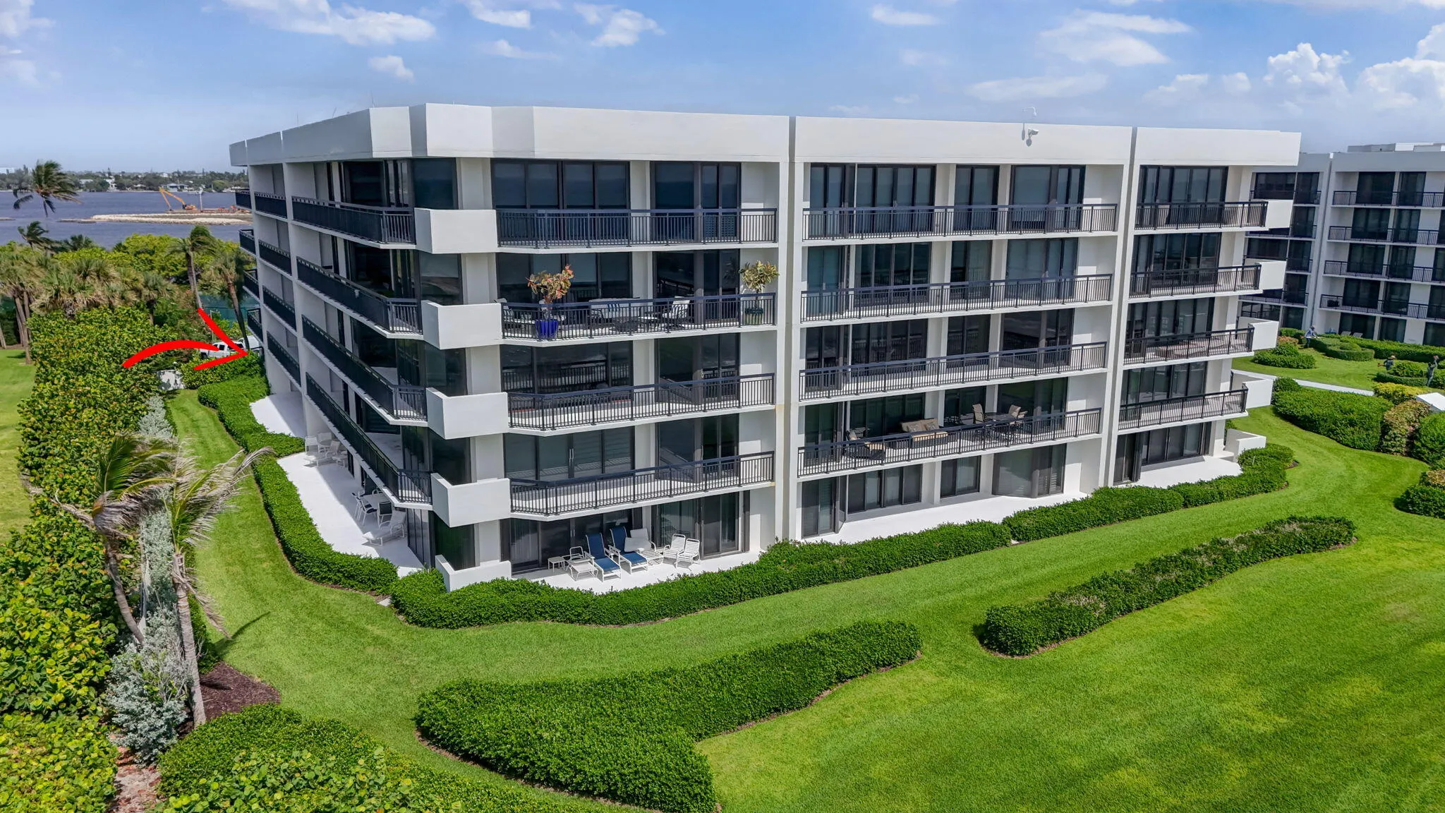 Contemporary multi-story building featuring expansive balconies, floor-to-ceiling glass doors, sleek black railings, and a white stucco exterior