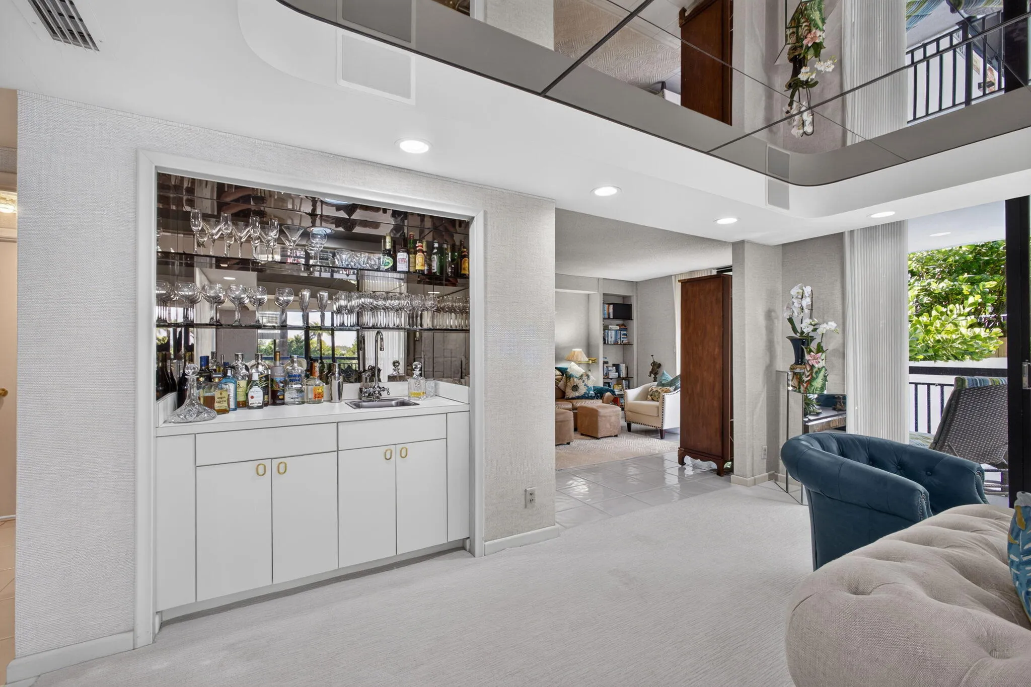 Built-in wet bar featuring white cabinetry, a countertop, and a mirrored backsplash with integrated stemware storage