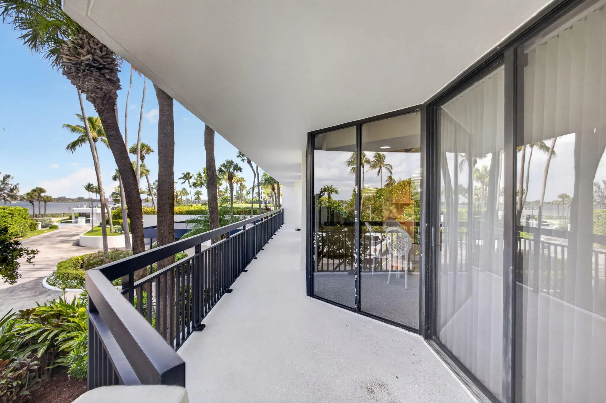 Exterior balcony featuring a concrete floor, black metal railings, and floor-to-ceiling sliding glass doors
