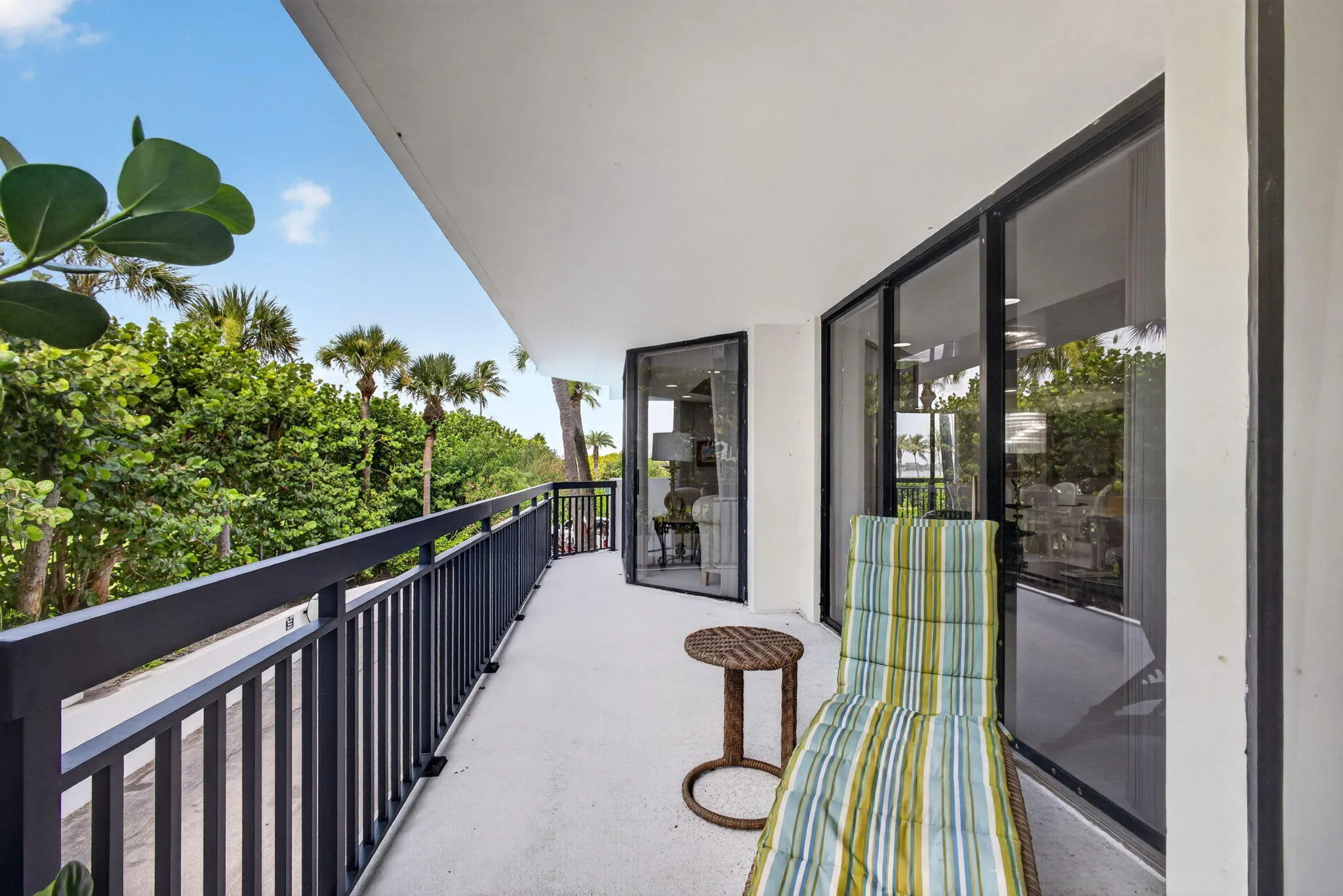 Spacious exterior balcony featuring a dark metal railing, concrete flooring, and sliding glass doors