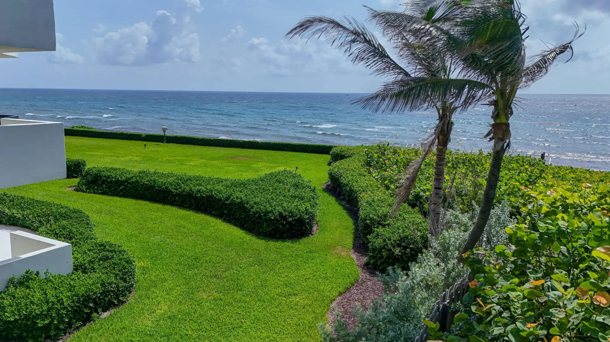Expansive green lawn and manicured hedges bordering the ocean