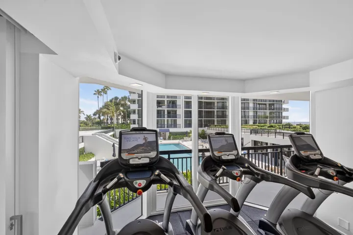 Fitness area featuring floor-to-ceiling windows, panoramic outdoor scenery, a swimming pool, and tropical foliage