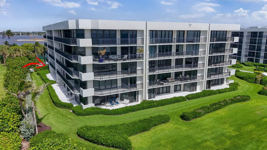 Contemporary multi-story building featuring expansive balconies, floor-to-ceiling glass doors, sleek black railings, and a white stucco exterior