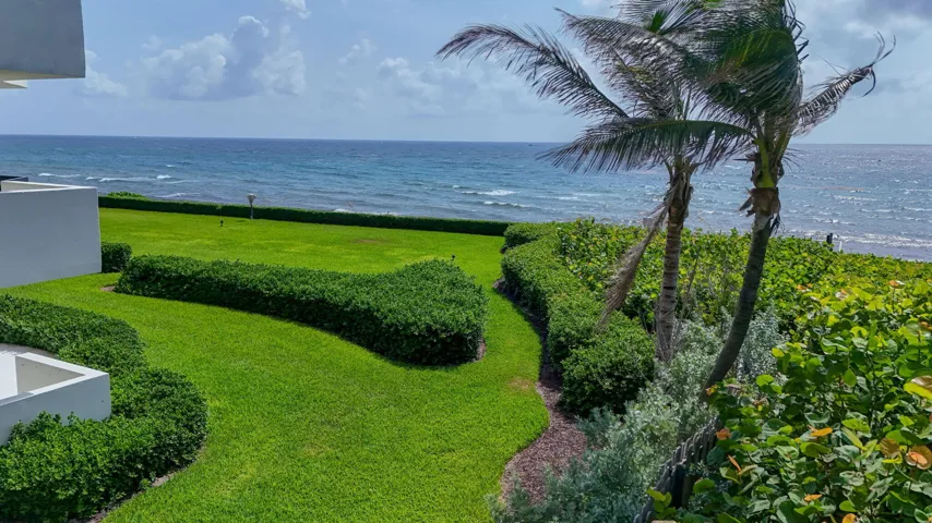 Expansive green lawn and manicured hedges bordering the ocean