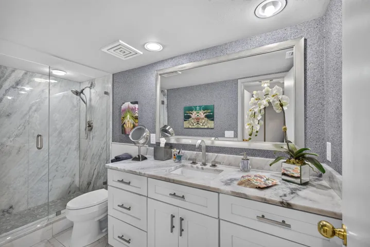 Bathroom featuring a white vanity with integrated sink, stone countertop, and a large wall-mounted mirror
