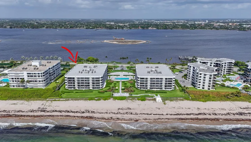 Beachfront residential building featuring multiple private balconies, landscaped grounds, a community pool, and direct beach access