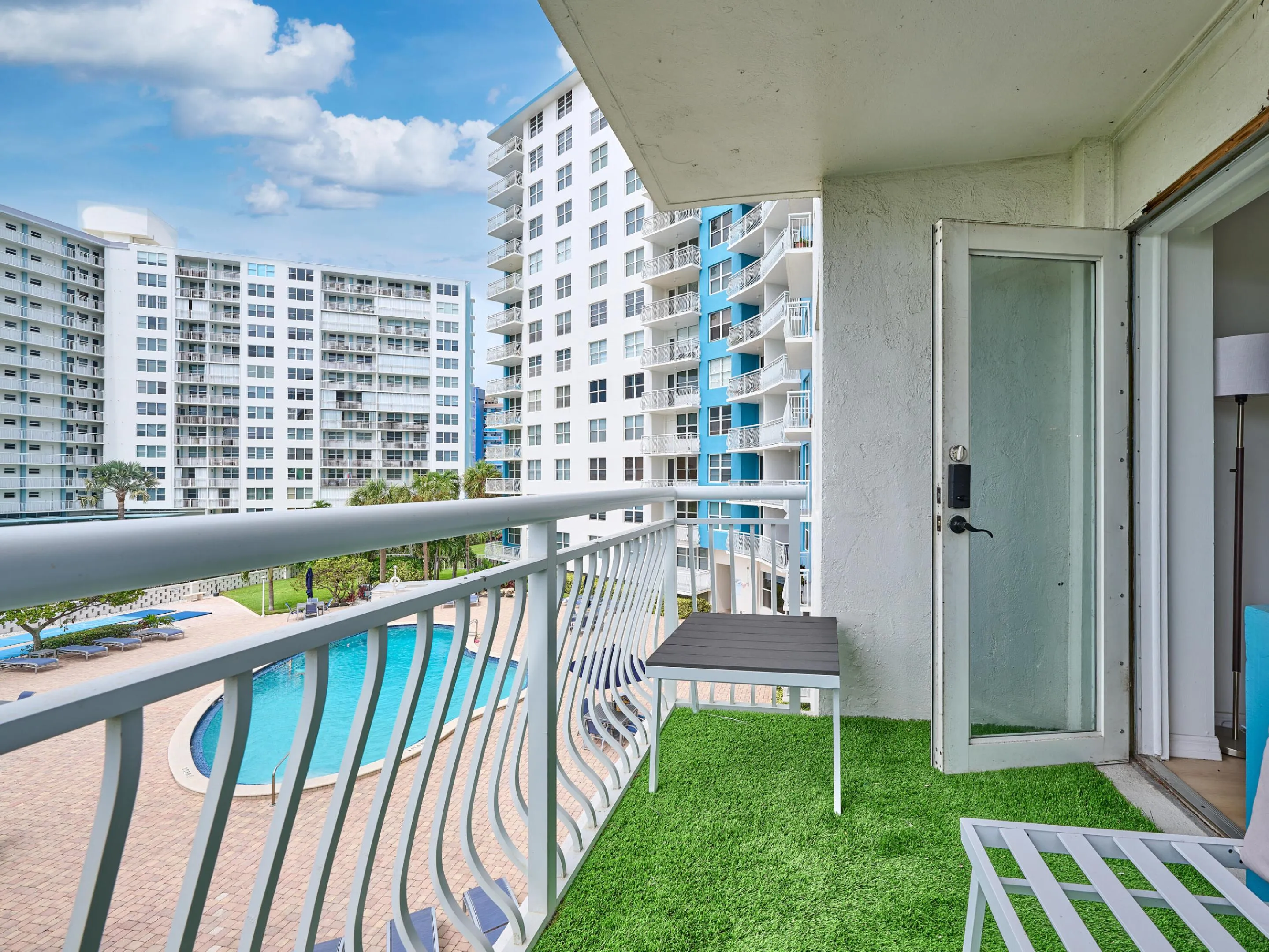 Balcony | Enjoy beautiful views of the swimming pool, lush landscaping, and blue skies.