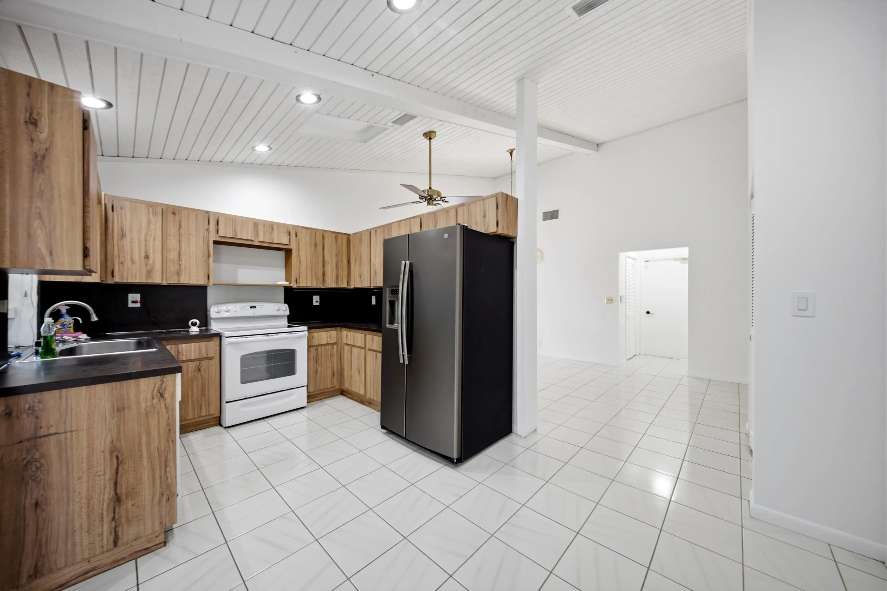 Kitchen featuring wood-finish cabinetry, dark countertops, and white tile flooring