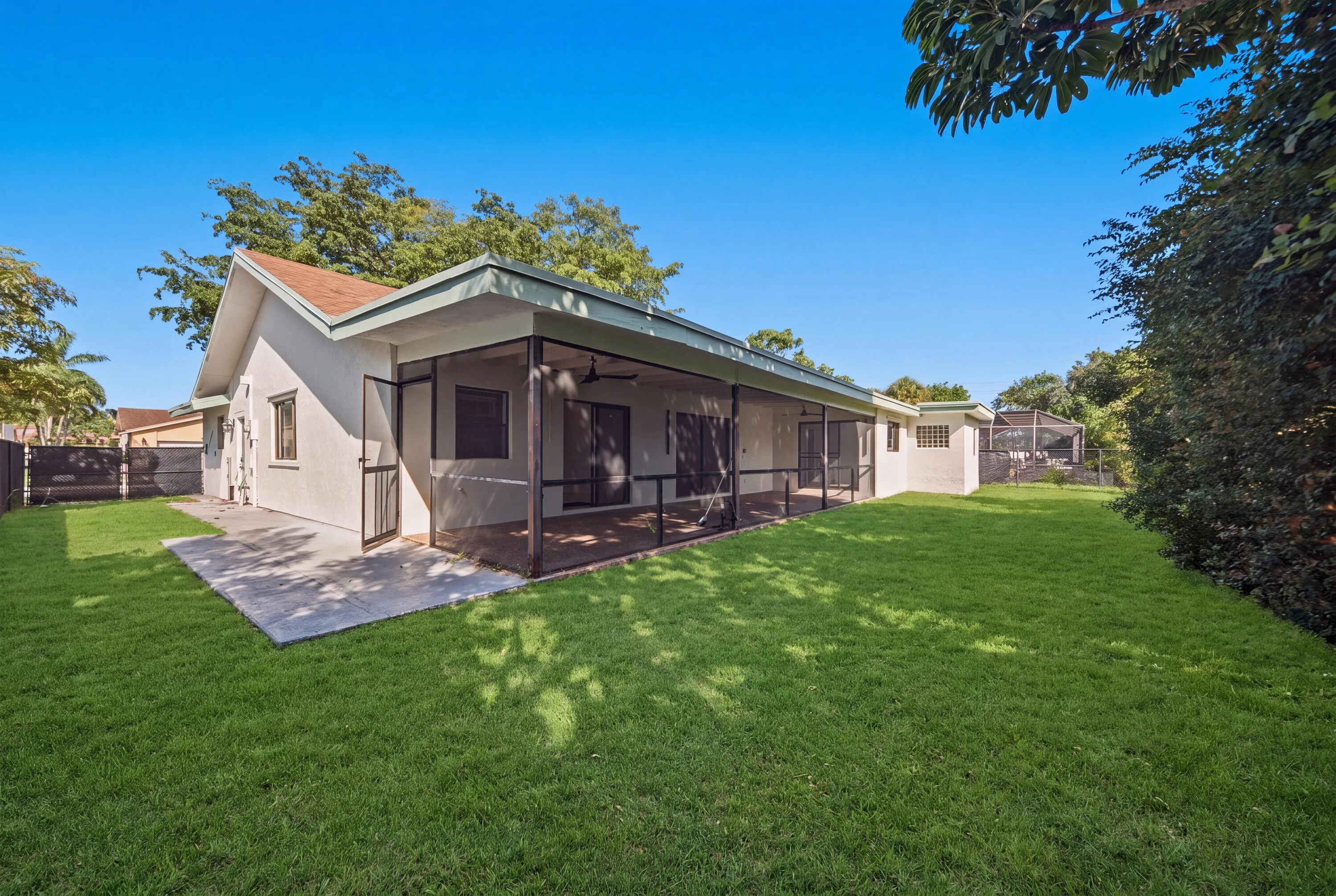 Expansive rear yard featuring a manicured lawn and mature landscaping