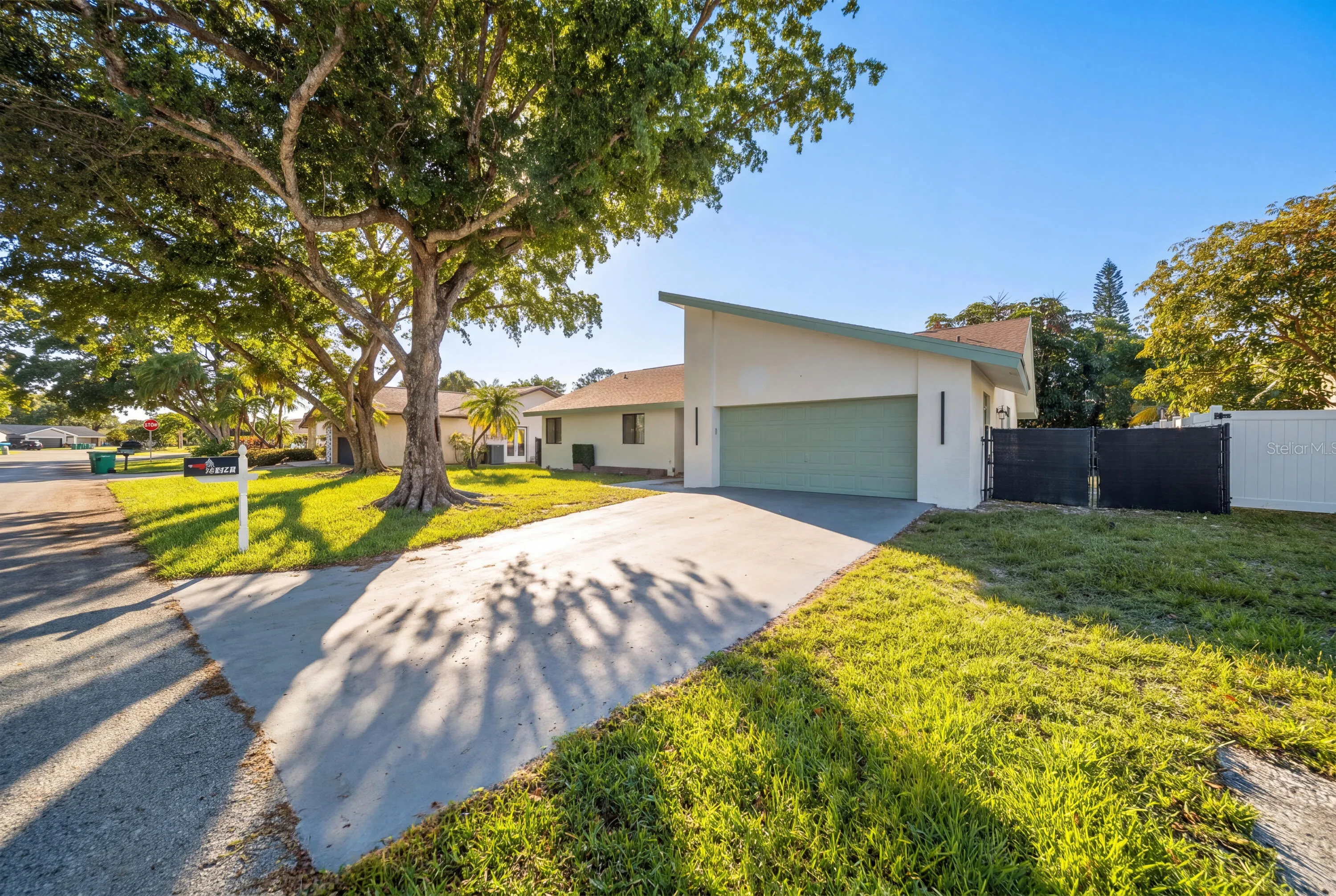 Contemporary facade with a muted green garage door, a prominent sloping roofline, and a concrete driveway
