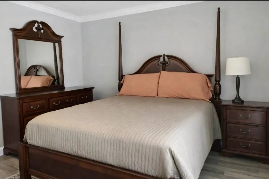 Bedroom featuring light grey walls, white crown molding, and wood-look vinyl flooring