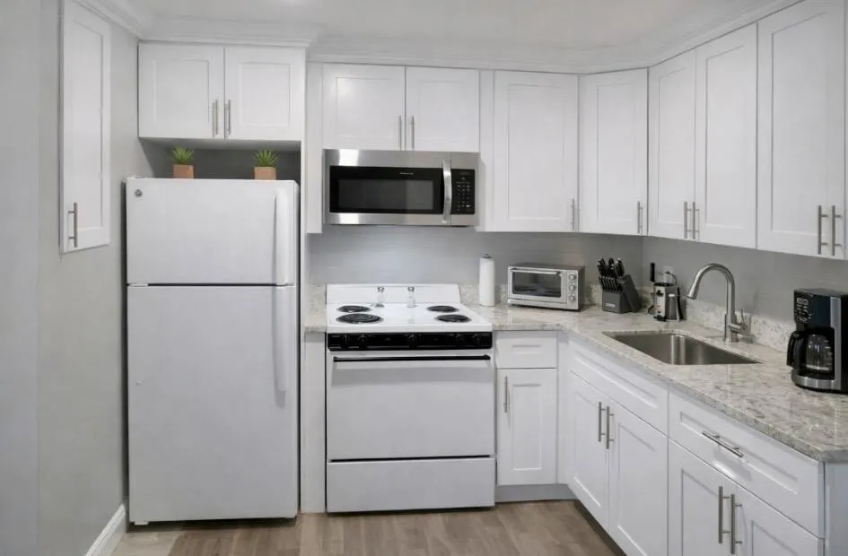 Well-appointed kitchen featuring white cabinetry, light-toned countertops, a stainless steel sink, wood-look vinyl flooring, and a stainless steel over-the-range microwave