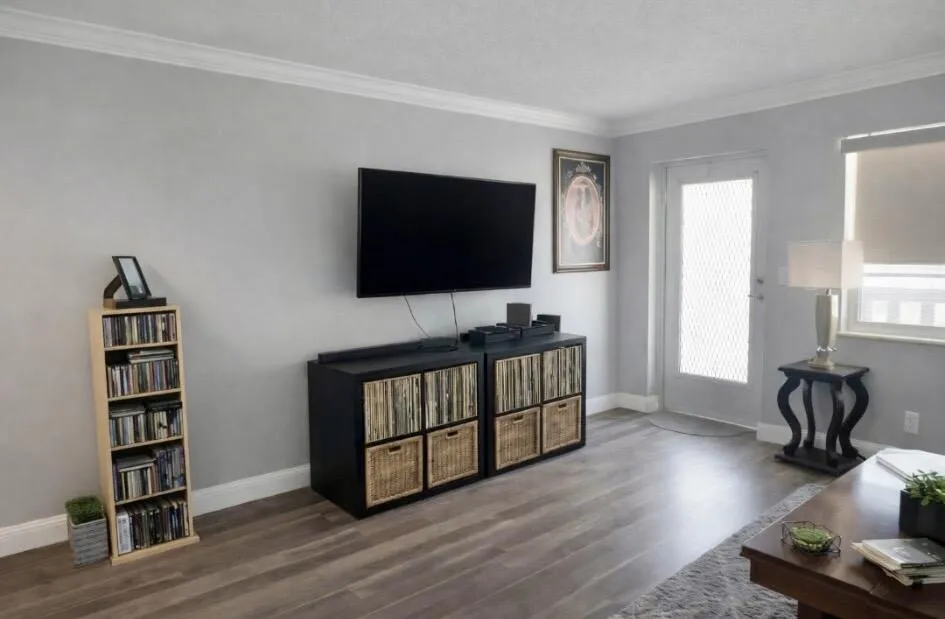 Living area featuring wood look vinyl flooring, light grey wall paint, and white crown molding