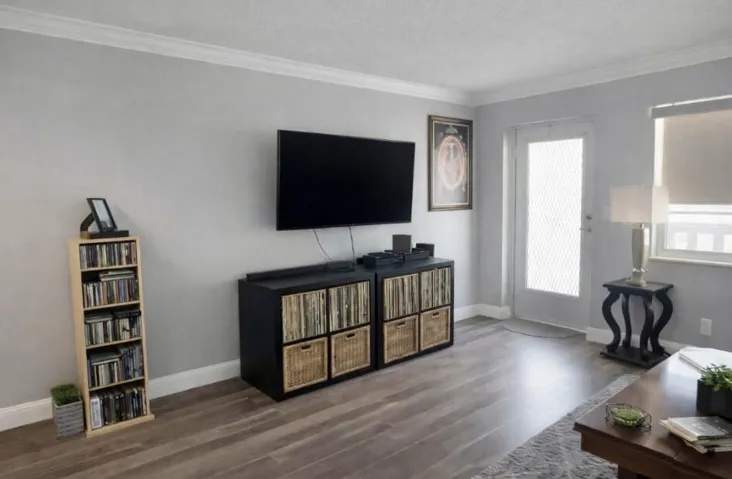 Living area featuring wood look vinyl flooring, light grey wall paint, and white crown molding