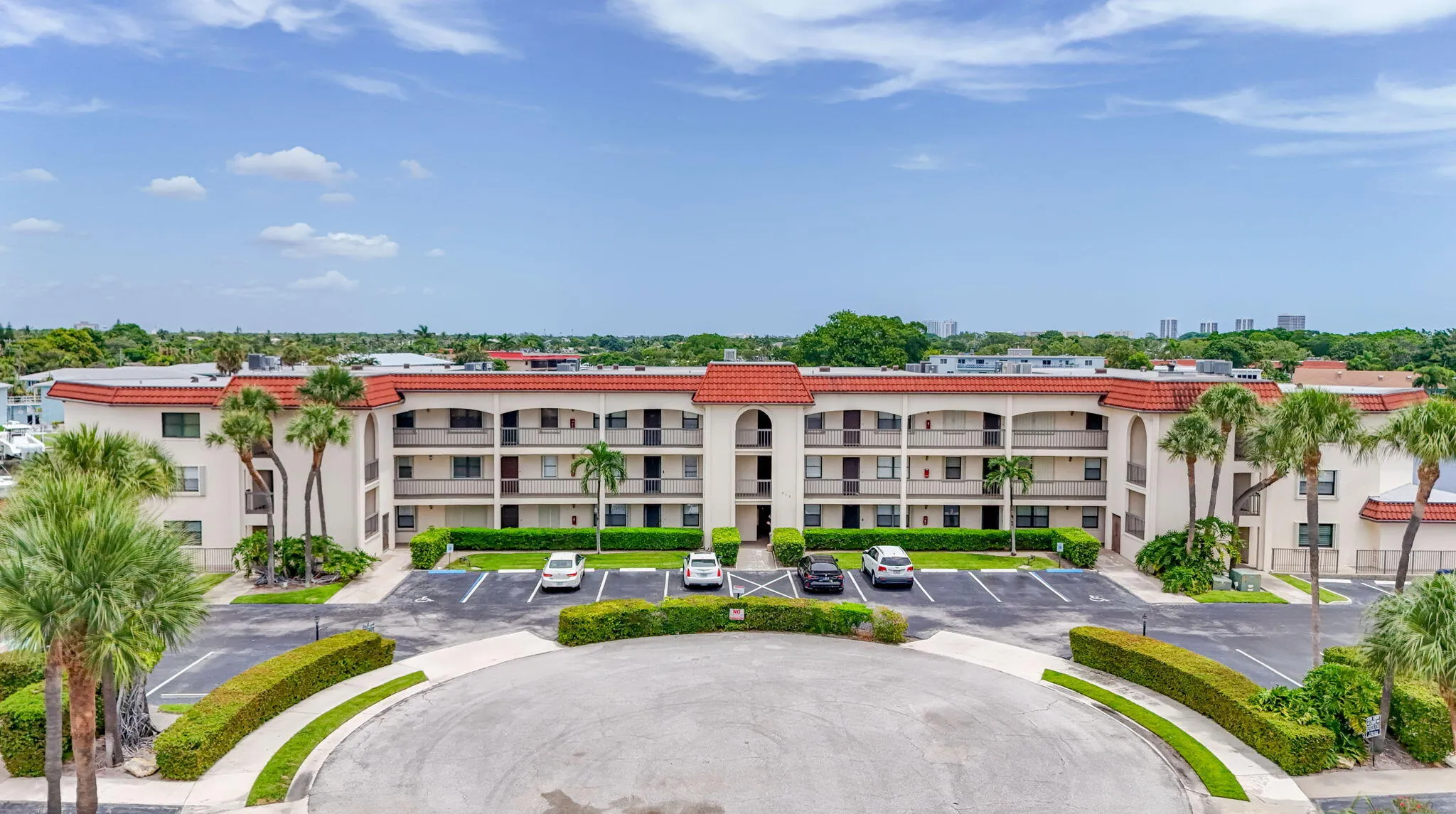 Mediterranean-inspired condominium building featuring a red tile roof and multiple private balconies