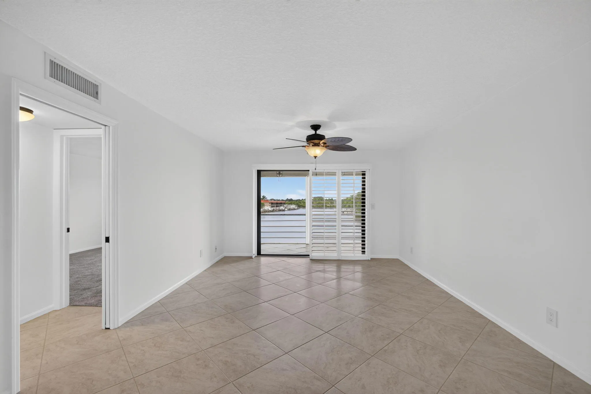 Spacious interior featuring neutral tile flooring, white walls, and a ceiling fan with integrated lighting