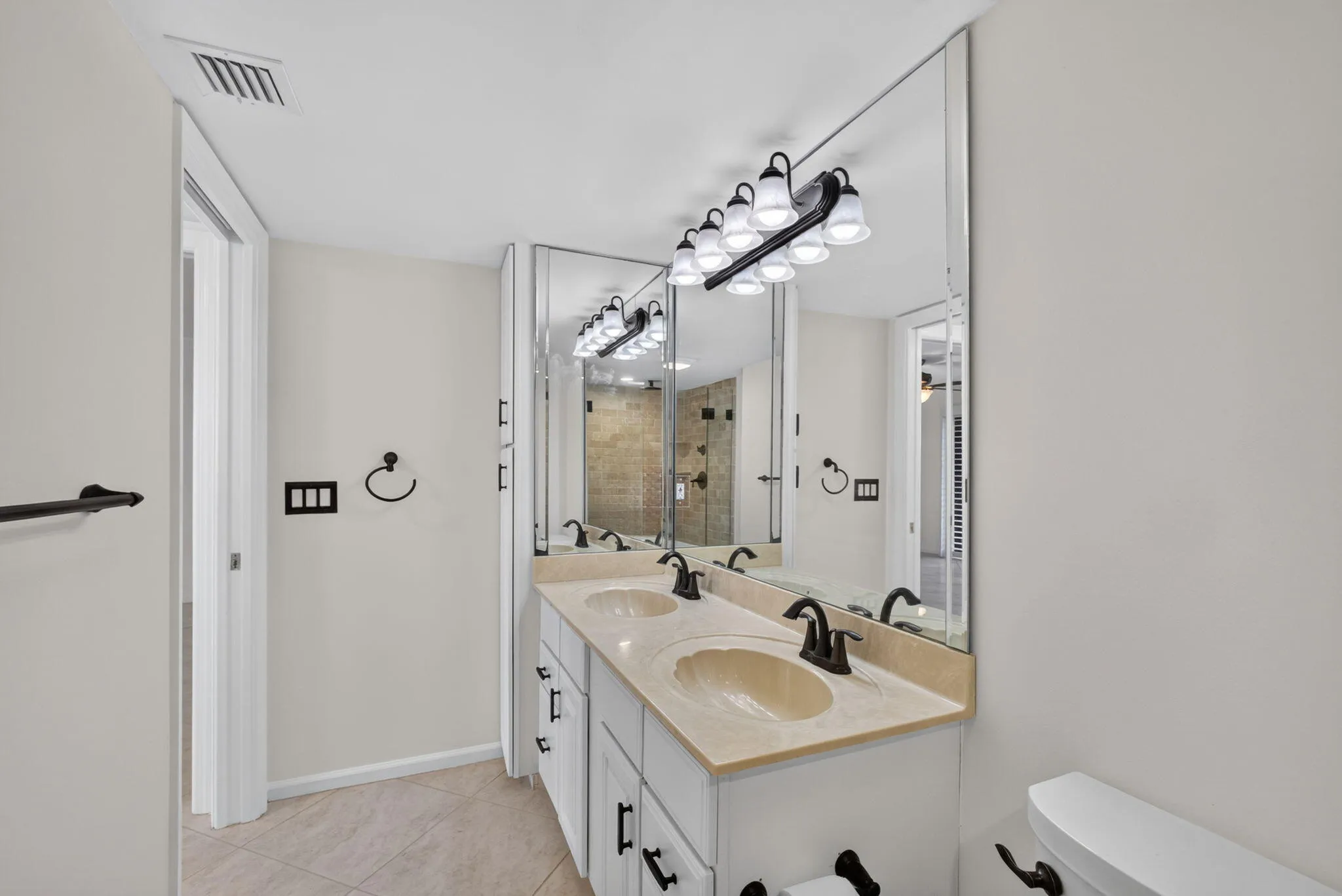 Dual sink vanity featuring a light-toned countertop, white cabinetry, and oil-rubbed bronze fixtures