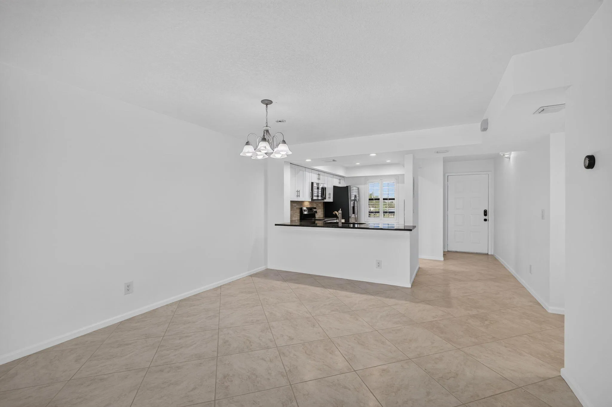Open-concept living space featuring neutral tone tile flooring and white painted walls
