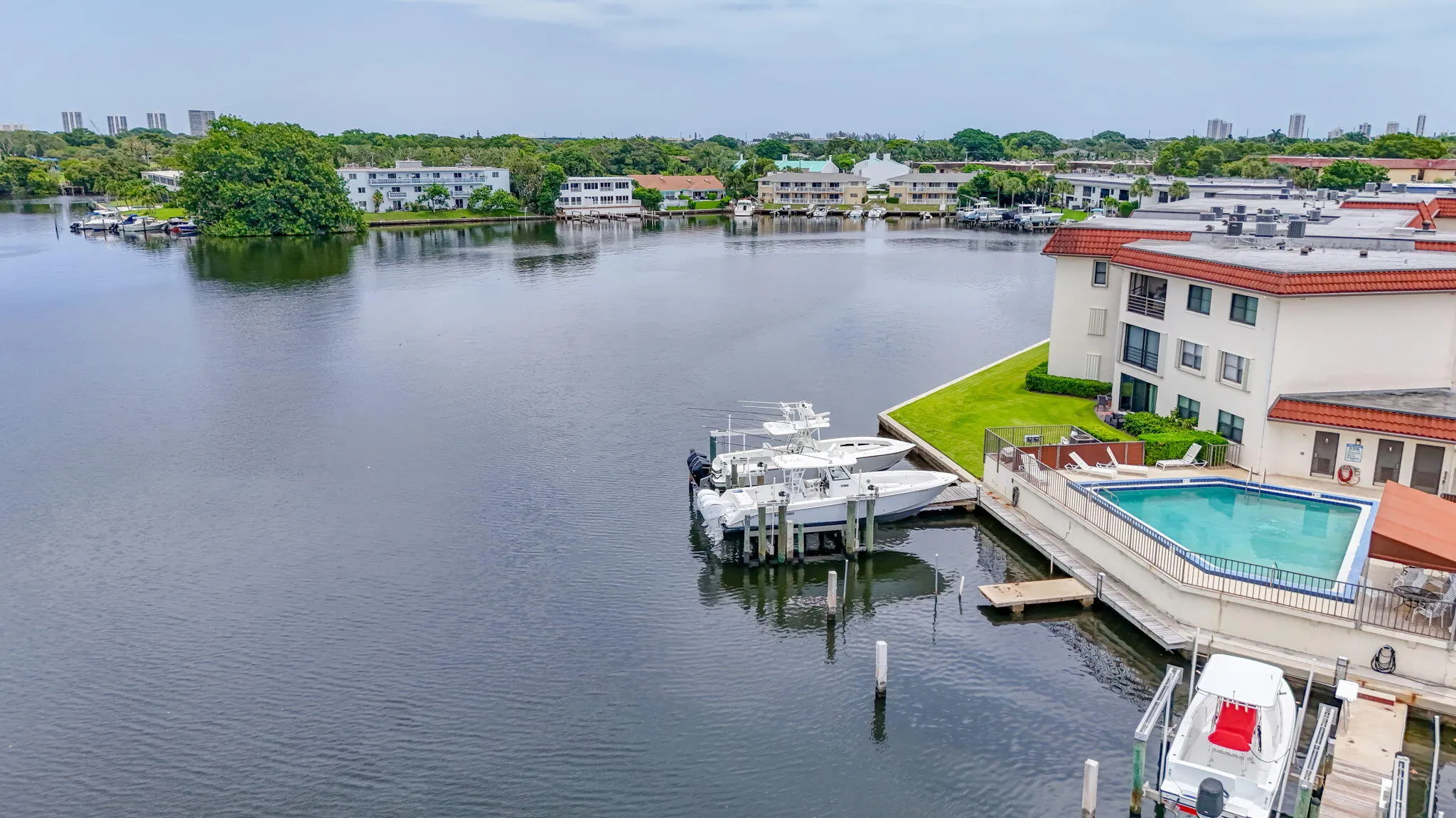 Waterfront property featuring a private boat dock, a swimming pool, and an adjacent building with multiple balconies