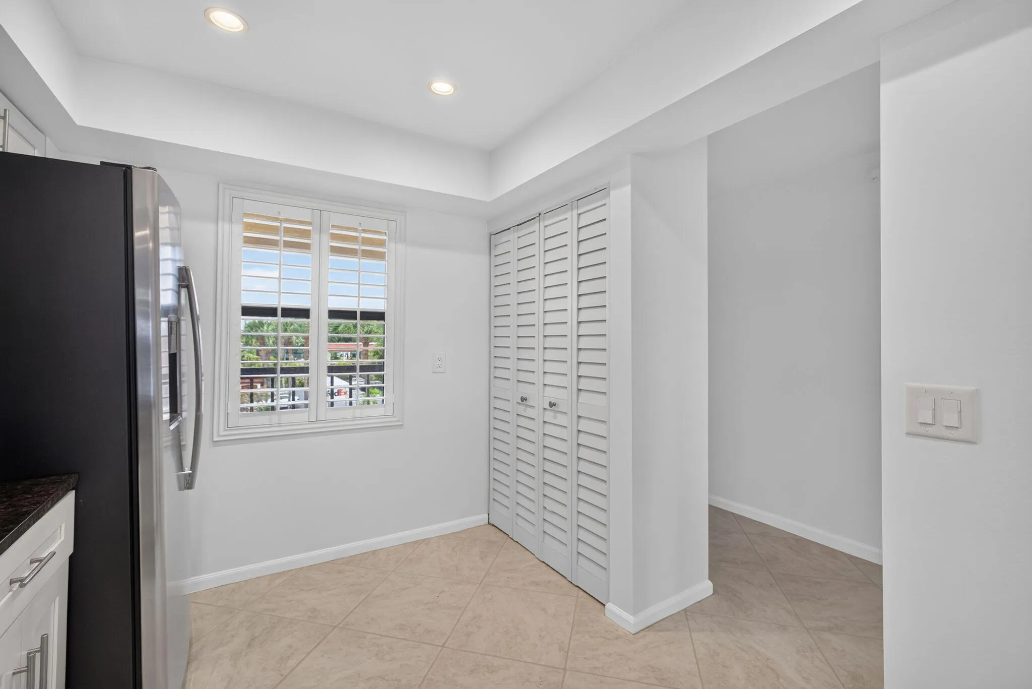 Kitchen area featuring recessed lighting, a stainless steel refrigerator, and plantation shutters on the window
