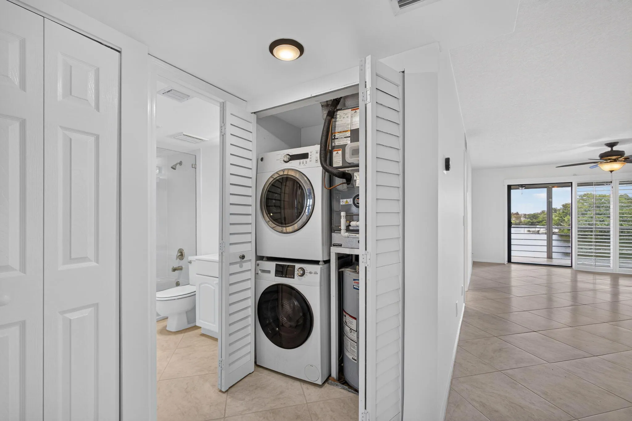 Integrated laundry closet with stacked washer and dryer, adjacent to a bathroom featuring a white vanity and toilet