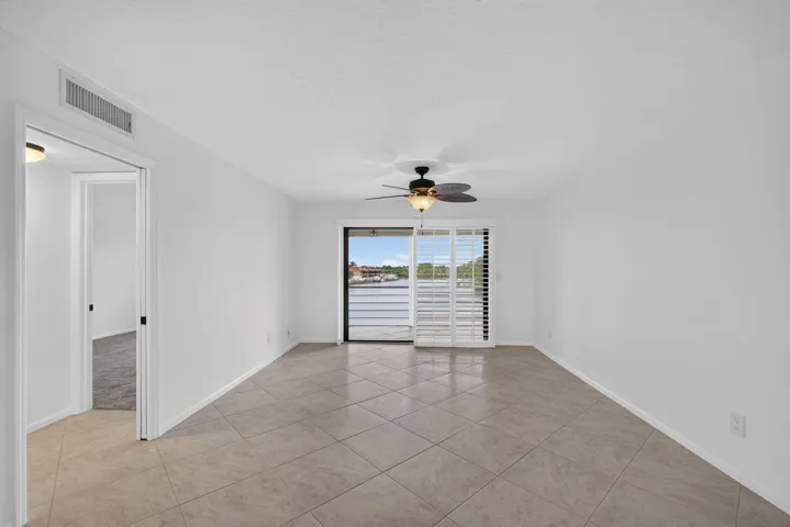 Spacious interior featuring neutral tile flooring, white walls, and a ceiling fan with integrated lighting
