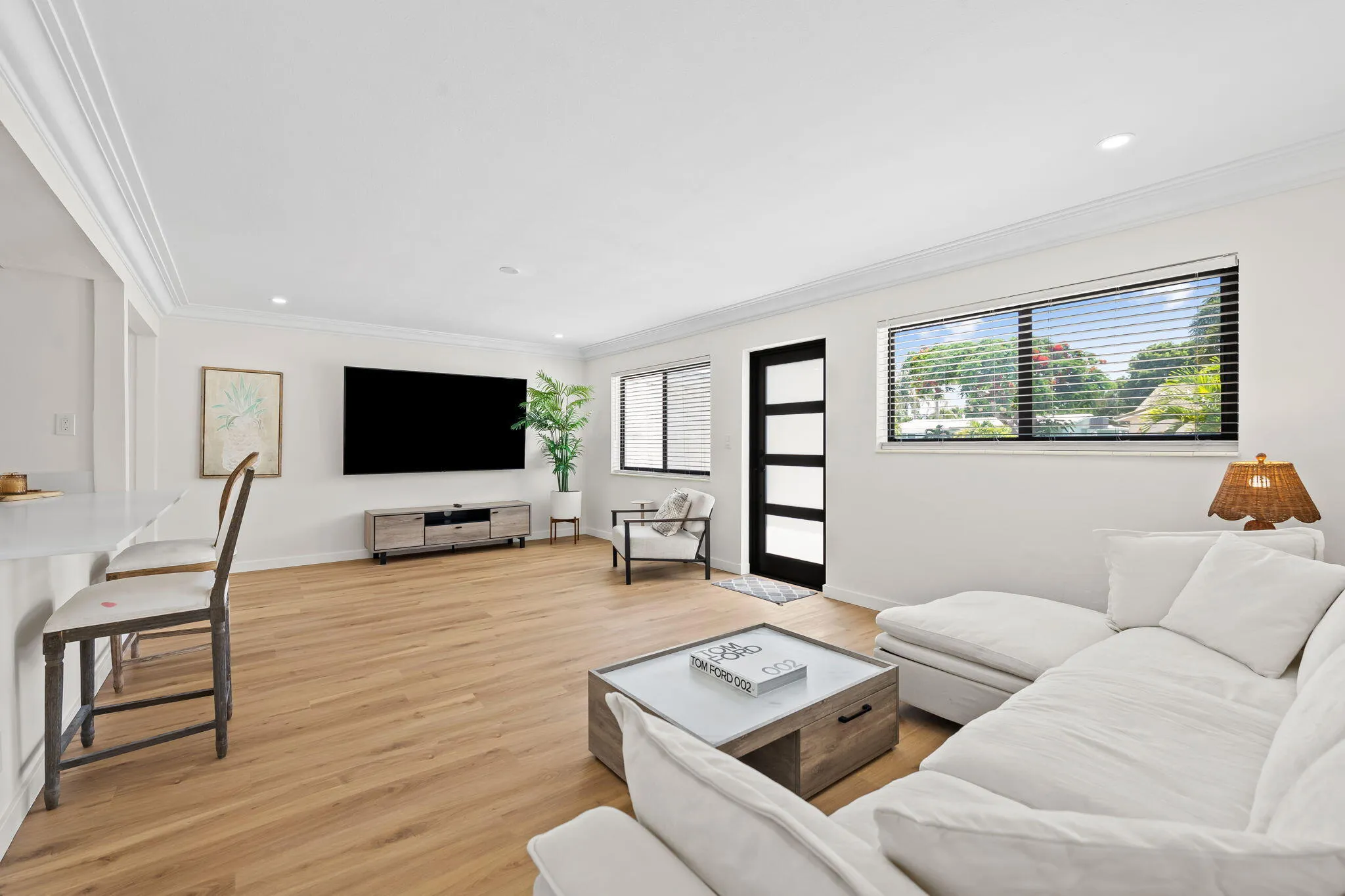 Spacious living area featuring wood-finish flooring, white crown molding, recessed lighting, and large windows with horizontal blinds