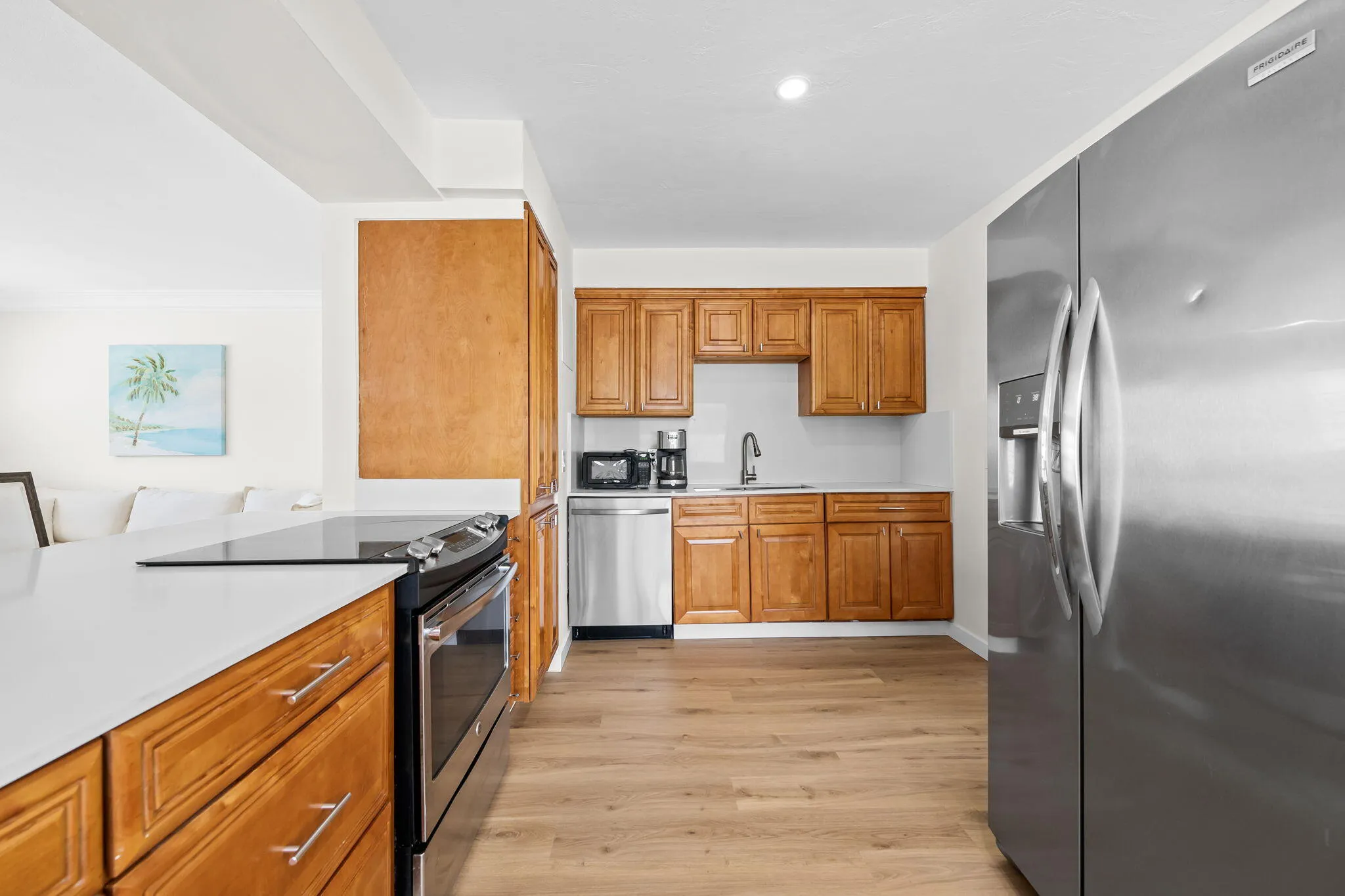 Kitchen featuring wood-finish cabinetry, stainless steel appliances, light-toned countertops, and wood-finish flooring