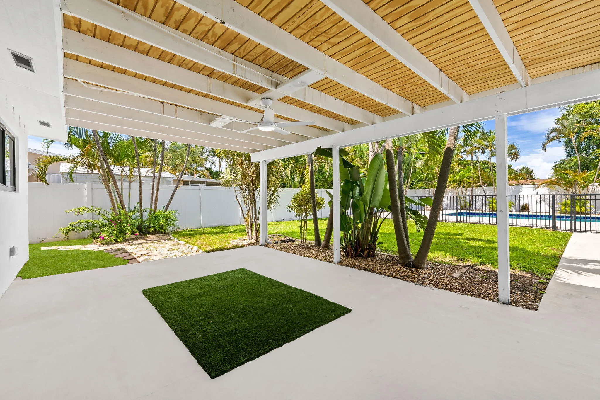 Covered patio featuring a slatted wood ceiling, a ceiling fan, and white painted beams