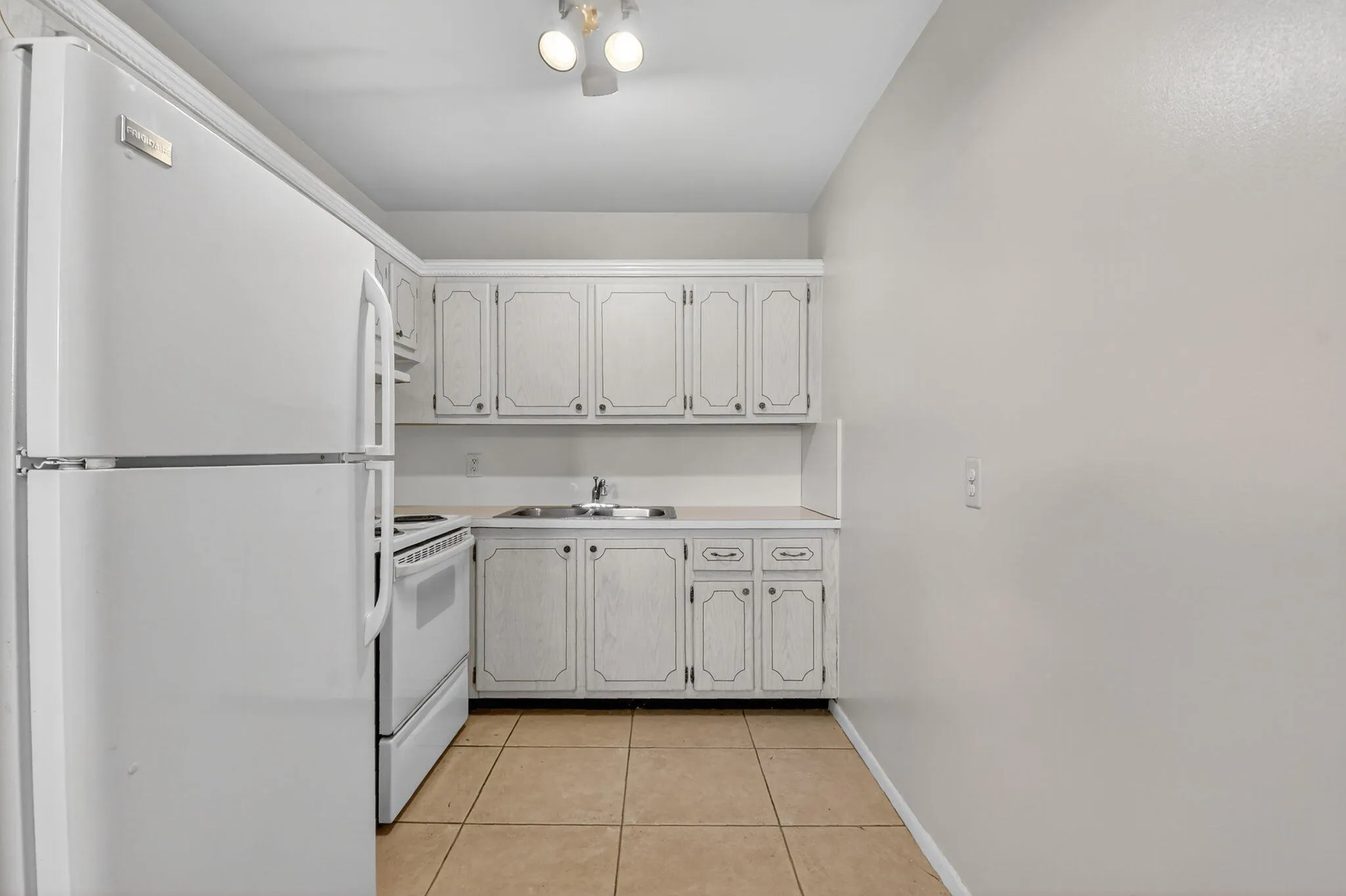 Compact kitchen featuring white appliances, including a refrigerator and electric range