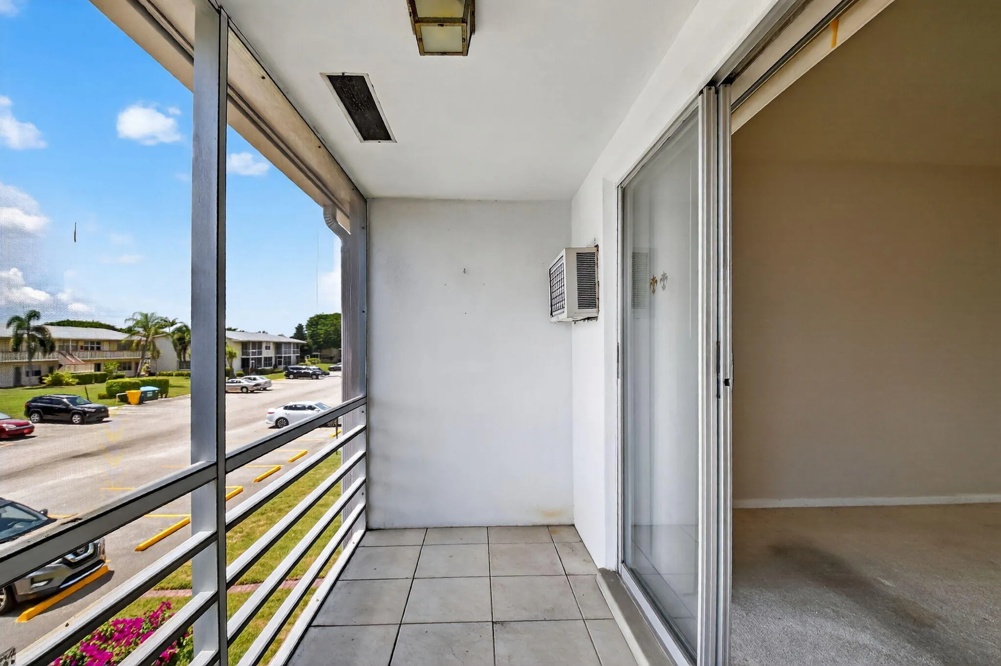Tiled balcony featuring white railings and a sliding glass door