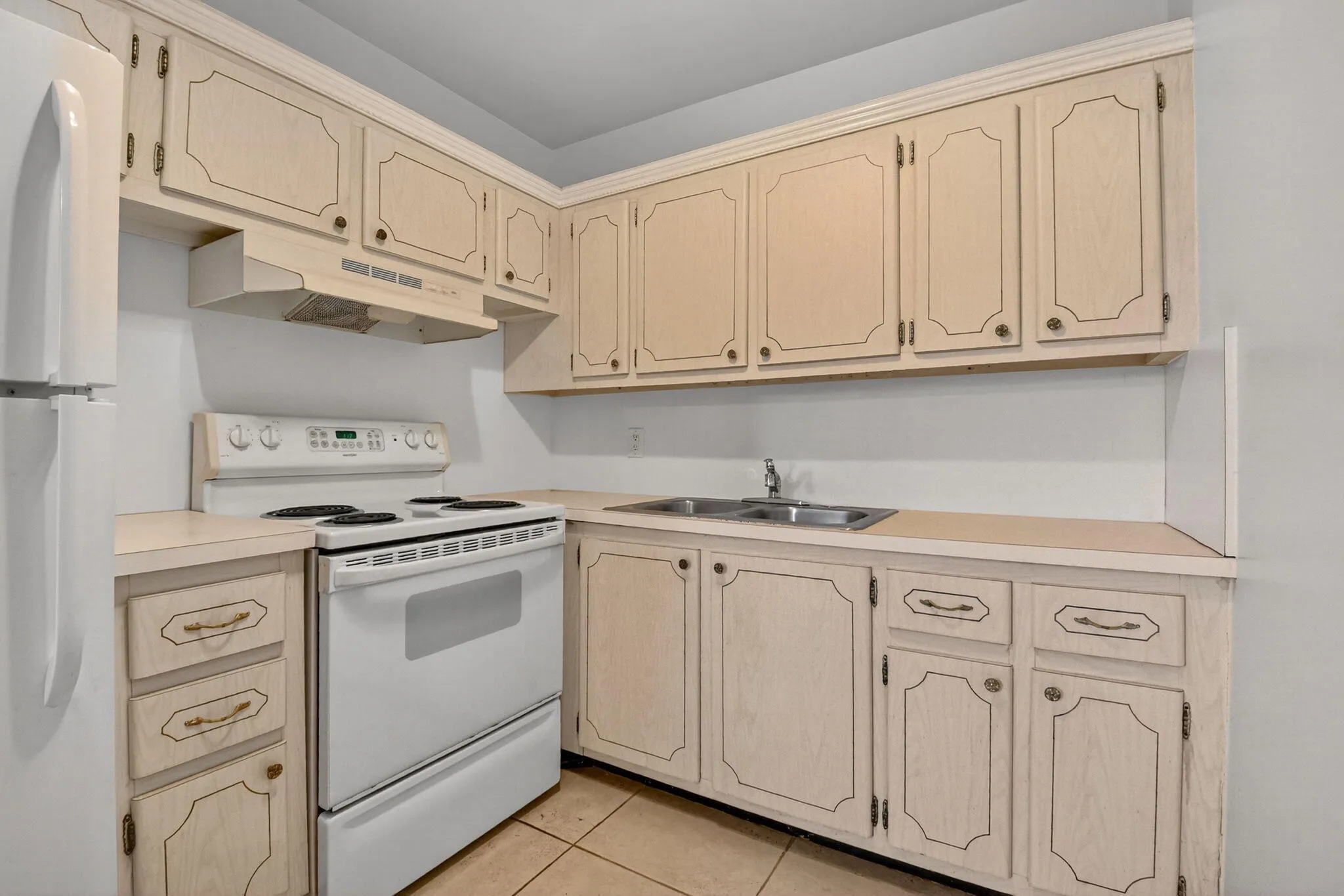 Kitchen featuring light-toned cabinetry, a white refrigerator, and a white electric range with coordinating range hood
