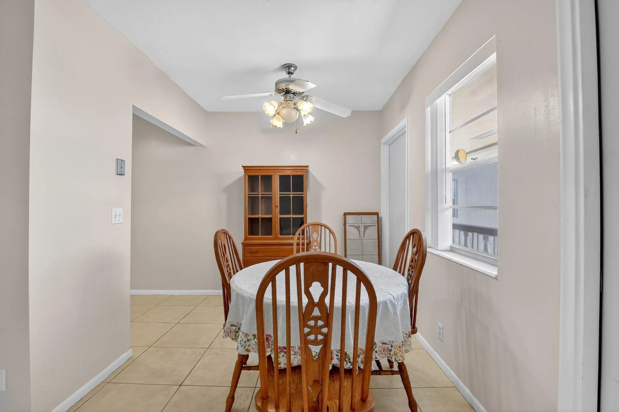 Dining area featuring neutral wall tones, tile flooring, a ceiling fan with integrated lighting, and natural light from a window