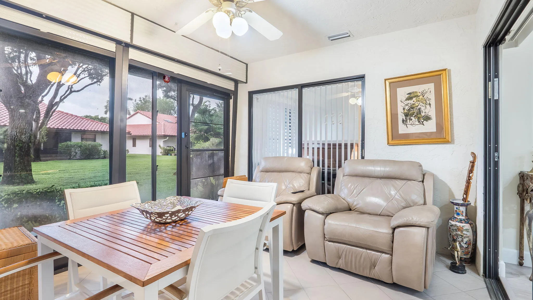 Sunroom featuring floor-to-ceiling sliding glass doors, white tile flooring, and a ceiling fan with integrated lighting